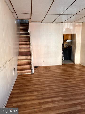 finished basement with a drop ceiling, wood finished floors, and stairs