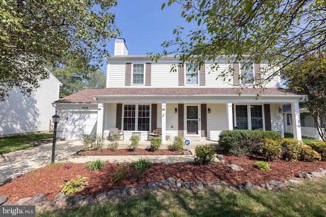 traditional-style house featuring a porch, a chimney, an attached garage, and concrete driveway