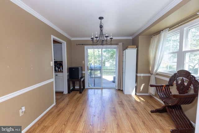 doorway to outside featuring a chandelier, plenty of natural light, light wood-style flooring, and ornamental molding