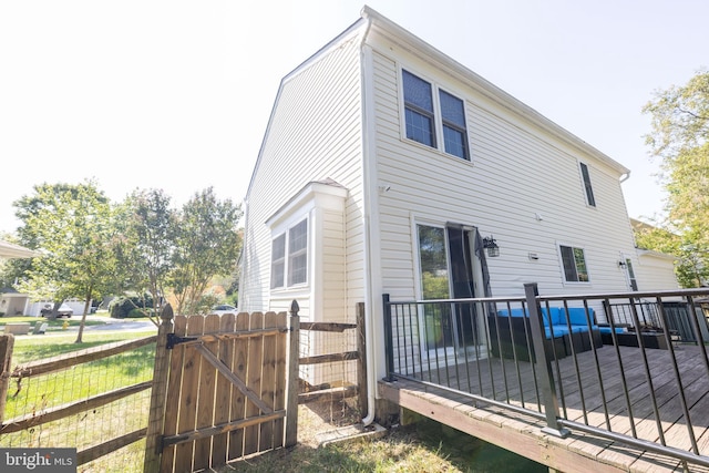 rear view of house with a deck, a gate, and fence