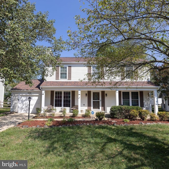 traditional home featuring a garage, driveway, a porch, and a front yard