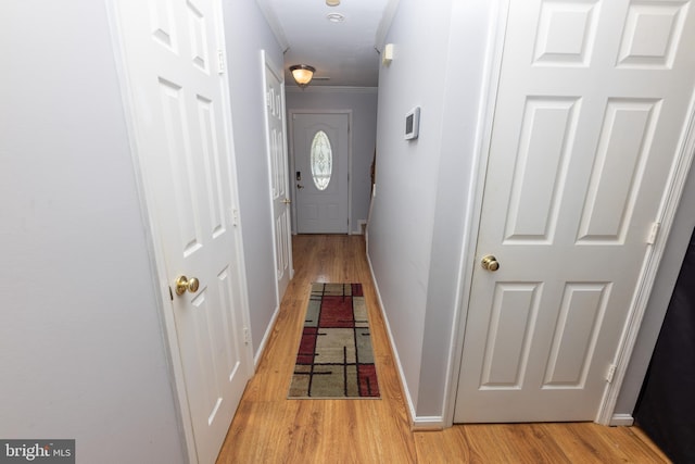 corridor with baseboards, light wood-style floors, and ornamental molding