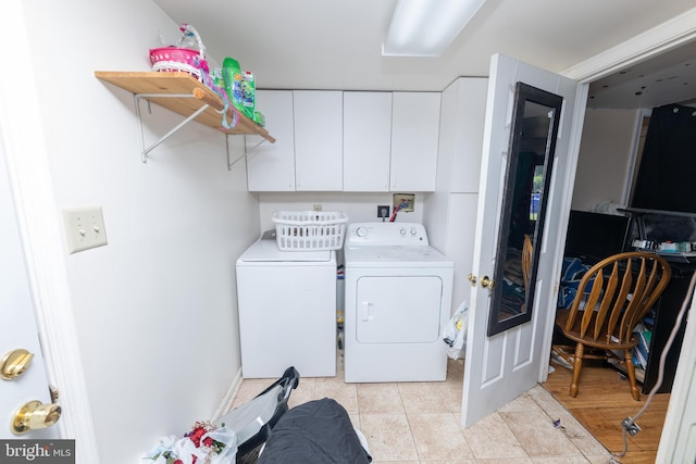 washroom featuring cabinet space, separate washer and dryer, and light tile patterned flooring