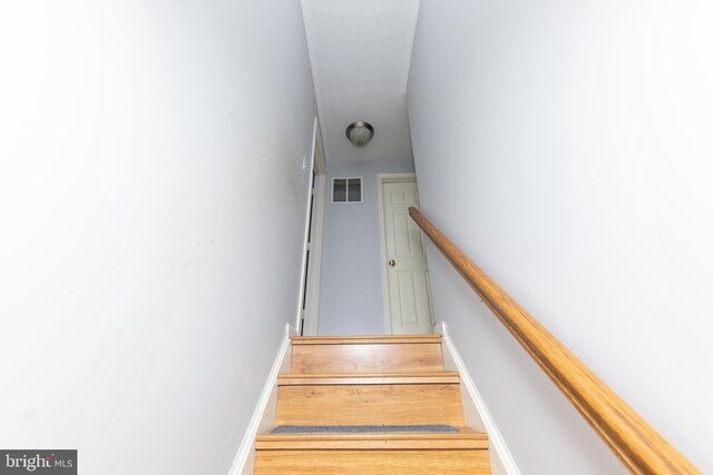 stairs with visible vents, baseboards, and wood finished floors