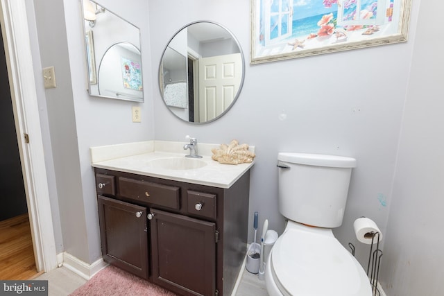 bathroom featuring vanity, toilet, and baseboards