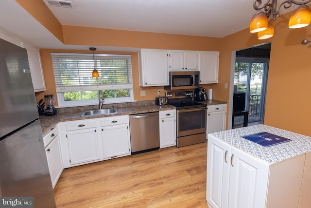 kitchen with a sink, white cabinets, a wealth of natural light, and stainless steel appliances