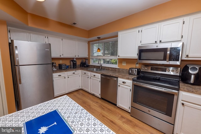 kitchen with light wood-type flooring, appliances with stainless steel finishes, and white cabinets