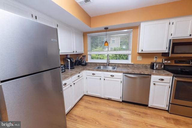 kitchen featuring visible vents, light wood-style flooring, a sink, stainless steel appliances, and white cabinets