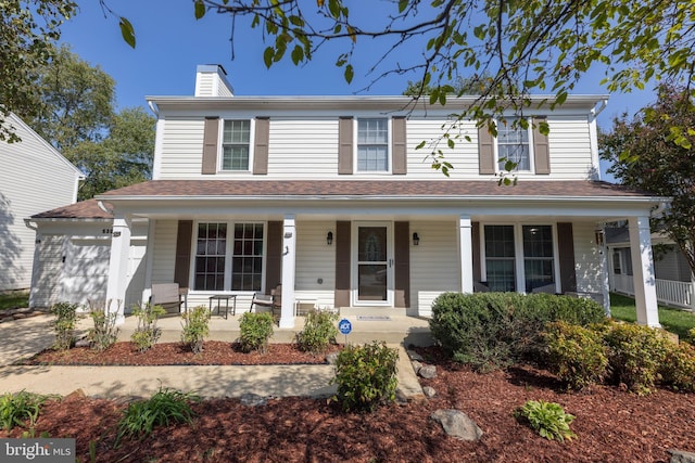 view of front of property with covered porch, an attached garage, and a chimney