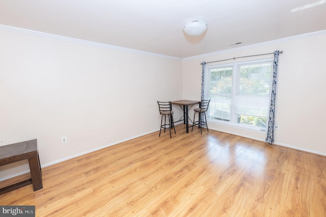 unfurnished room with visible vents, wood finished floors, baseboards, and ornamental molding