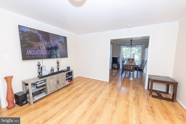 living area with a notable chandelier, light wood-type flooring, baseboards, and ornamental molding