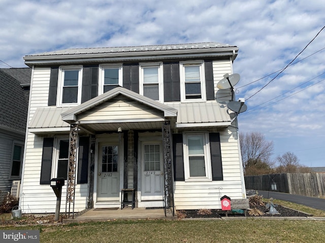 view of front facade featuring fence, covered porch, and metal roof