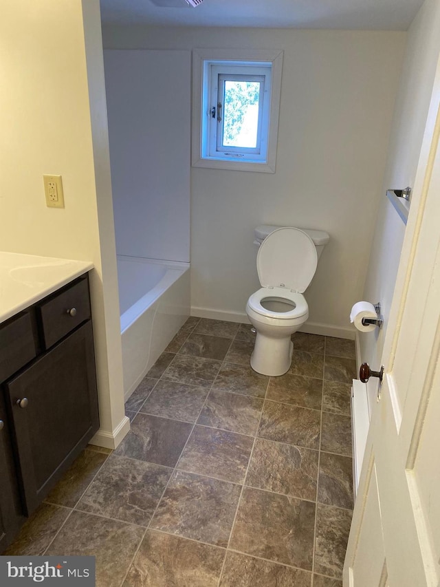 bathroom featuring vanity, toilet, a tub, and baseboards