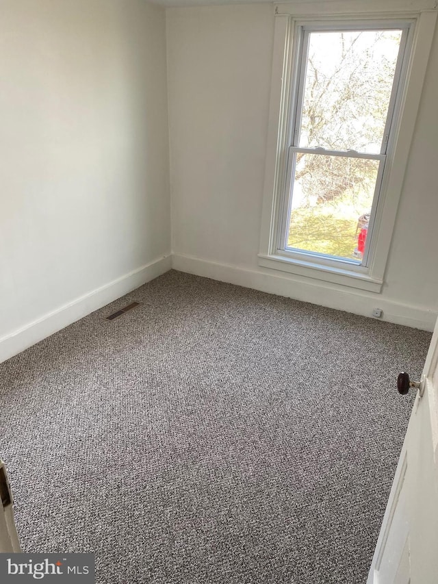 carpeted spare room featuring visible vents and baseboards