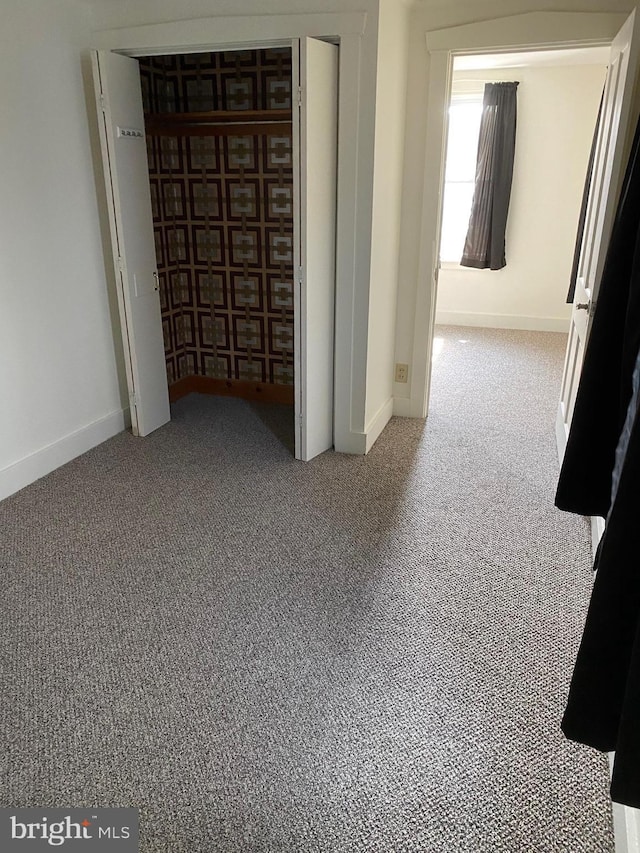 unfurnished bedroom featuring a closet, baseboards, and carpet floors