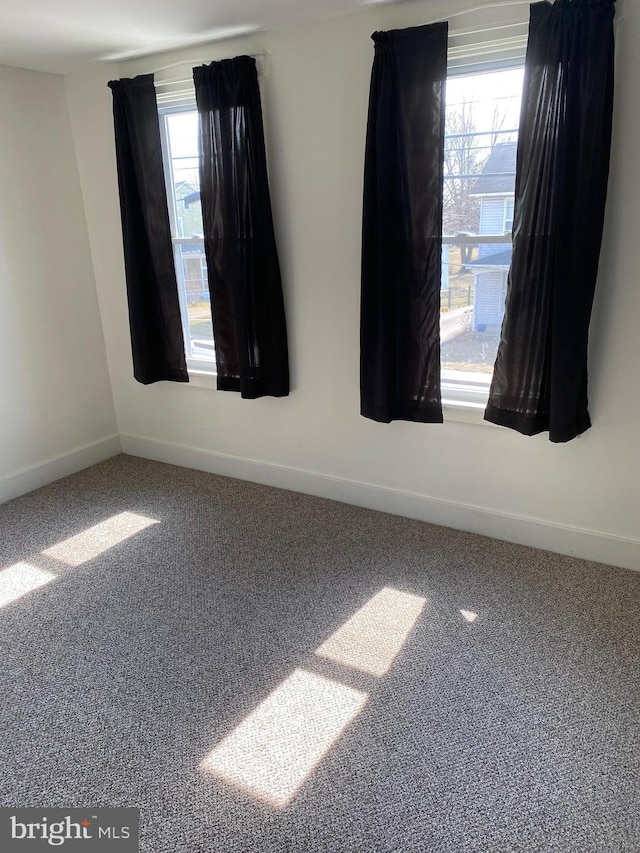 unfurnished room featuring plenty of natural light, baseboards, and carpet floors