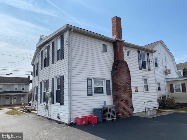 rear view of property with central AC unit and a chimney