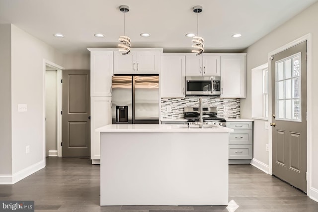 kitchen with backsplash, dark wood-type flooring, decorative light fixtures, light countertops, and stainless steel appliances