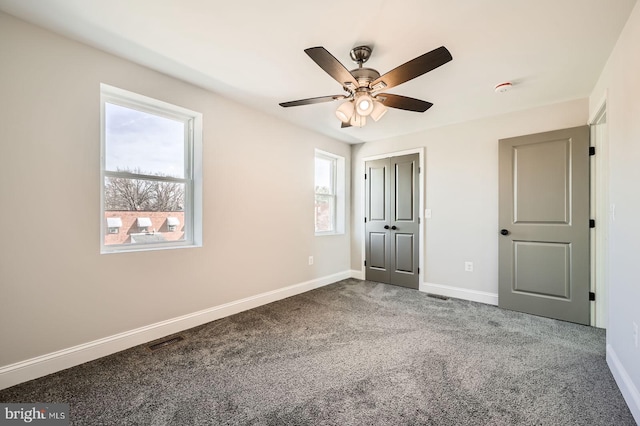 unfurnished bedroom featuring baseboards, visible vents, carpet floors, and ceiling fan