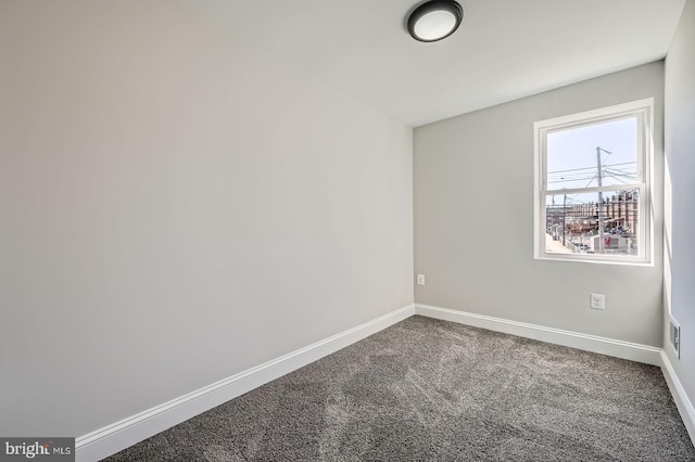 empty room with baseboards and dark colored carpet