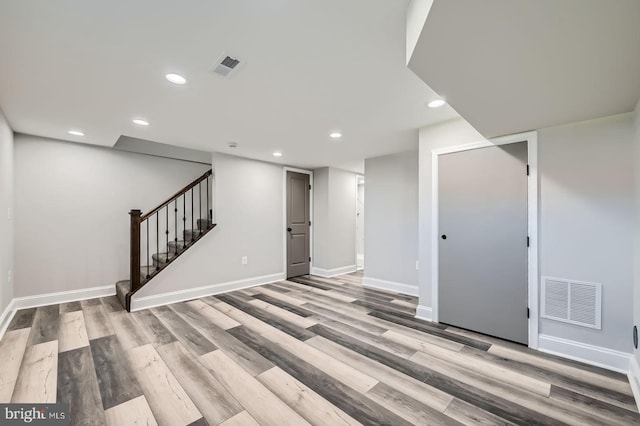 finished basement with stairway, recessed lighting, light wood-style floors, and visible vents