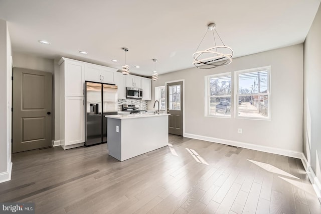 kitchen featuring backsplash, an island with sink, light countertops, appliances with stainless steel finishes, and white cabinets