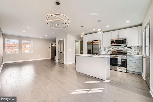 kitchen with decorative light fixtures, tasteful backsplash, stainless steel appliances, light wood-style floors, and light countertops