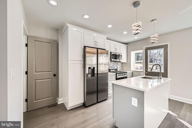 kitchen featuring backsplash, stainless steel appliances, light wood-style floors, white cabinetry, and a sink