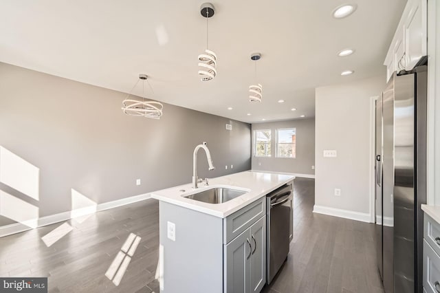 kitchen with dark wood-style flooring, gray cabinetry, stainless steel appliances, light countertops, and a sink