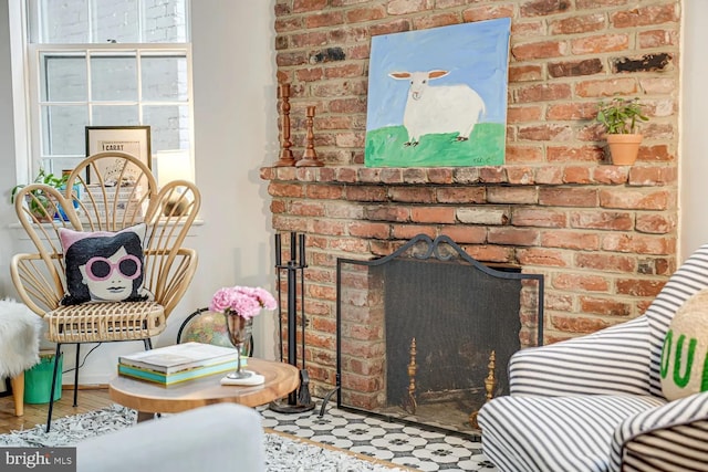 living room featuring a brick fireplace and wood finished floors