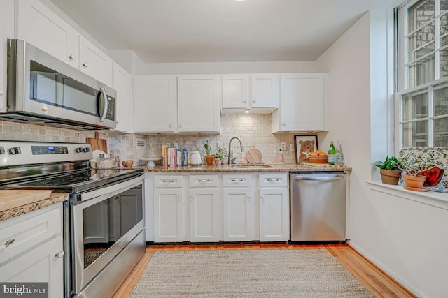 kitchen featuring a sink, decorative backsplash, appliances with stainless steel finishes, and white cabinets