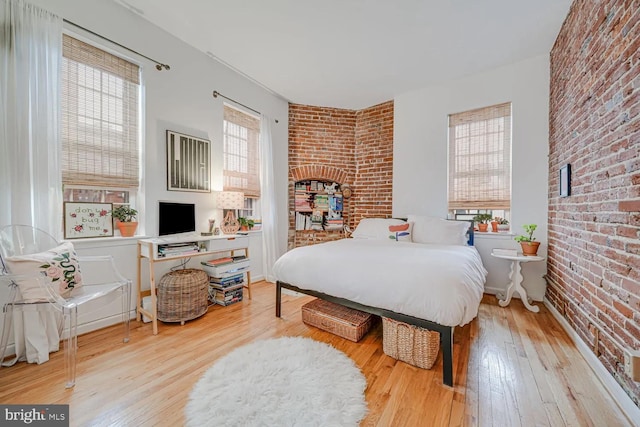 bedroom featuring wood-type flooring and brick wall