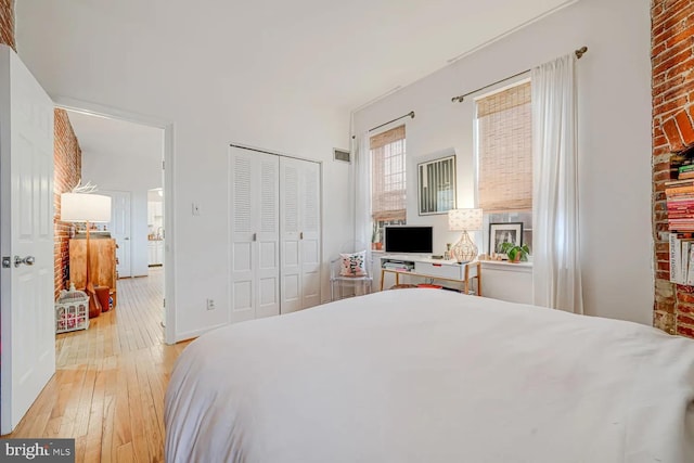 bedroom with visible vents, a closet, light wood finished floors, and baseboards