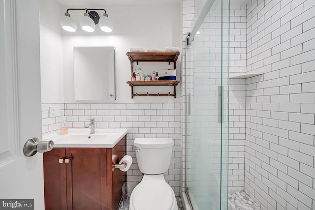 bathroom with tile walls, a shower stall, toilet, and vanity