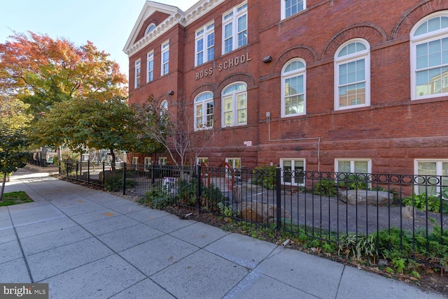 view of side of property featuring brick siding and fence