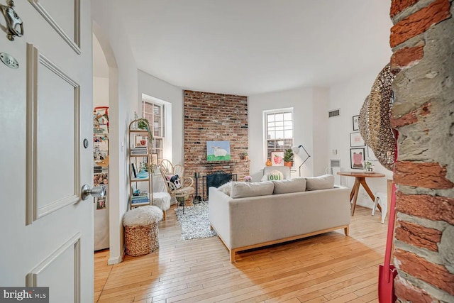 living area with a brick fireplace and light wood-style flooring