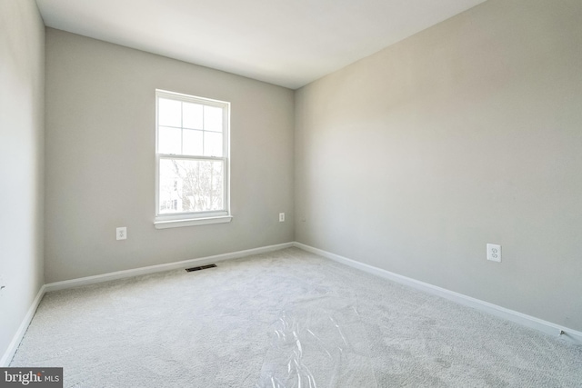 carpeted spare room featuring visible vents and baseboards