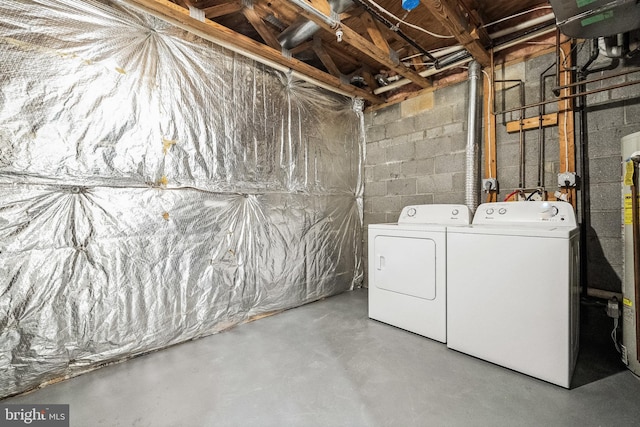 unfinished below grade area featuring concrete block wall and washing machine and clothes dryer