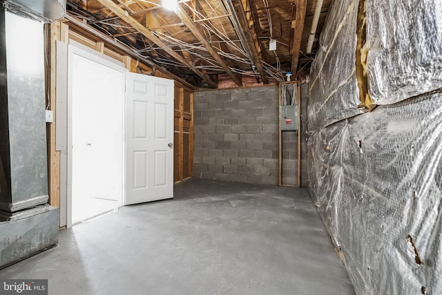 unfinished basement featuring concrete block wall and electric panel