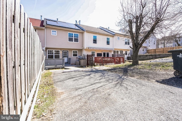 back of property with solar panels, fence, and a wooden deck