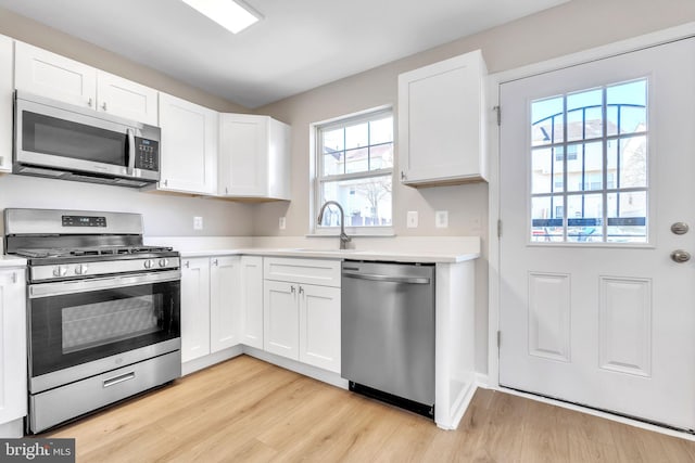 kitchen featuring a sink, stainless steel appliances, light wood-style flooring, and light countertops