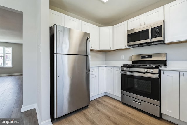 kitchen with light countertops, white cabinets, light wood-type flooring, and stainless steel appliances