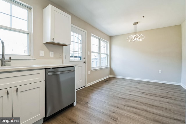 kitchen featuring dishwasher, light wood-style flooring, an inviting chandelier, white cabinetry, and a sink