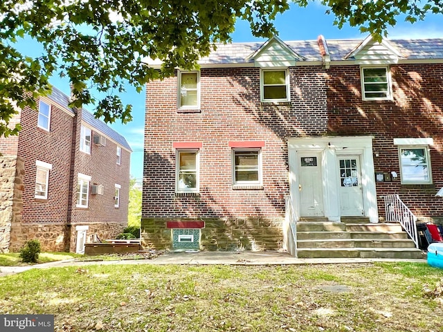 view of property featuring brick siding, a patio area, and a front lawn