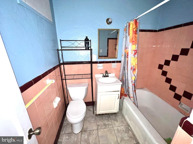 bathroom with tile walls, toilet, shower / bath combo with shower curtain, and tile patterned floors