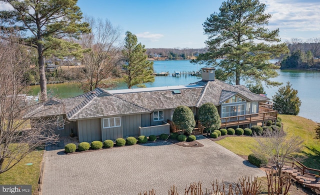 view of front of house featuring a water view, a front yard, a chimney, and driveway