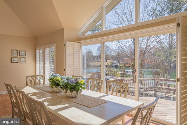 tiled dining area with baseboards, a water view, and high vaulted ceiling