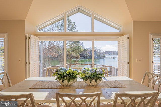 dining room with lofted ceiling and a water view