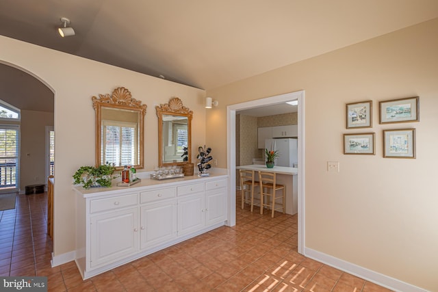 bathroom featuring tile patterned flooring, lofted ceiling, and baseboards