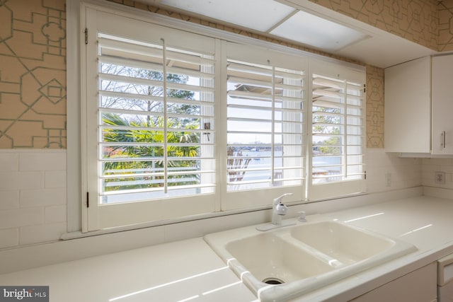 kitchen featuring white cabinetry, light countertops, and a sink